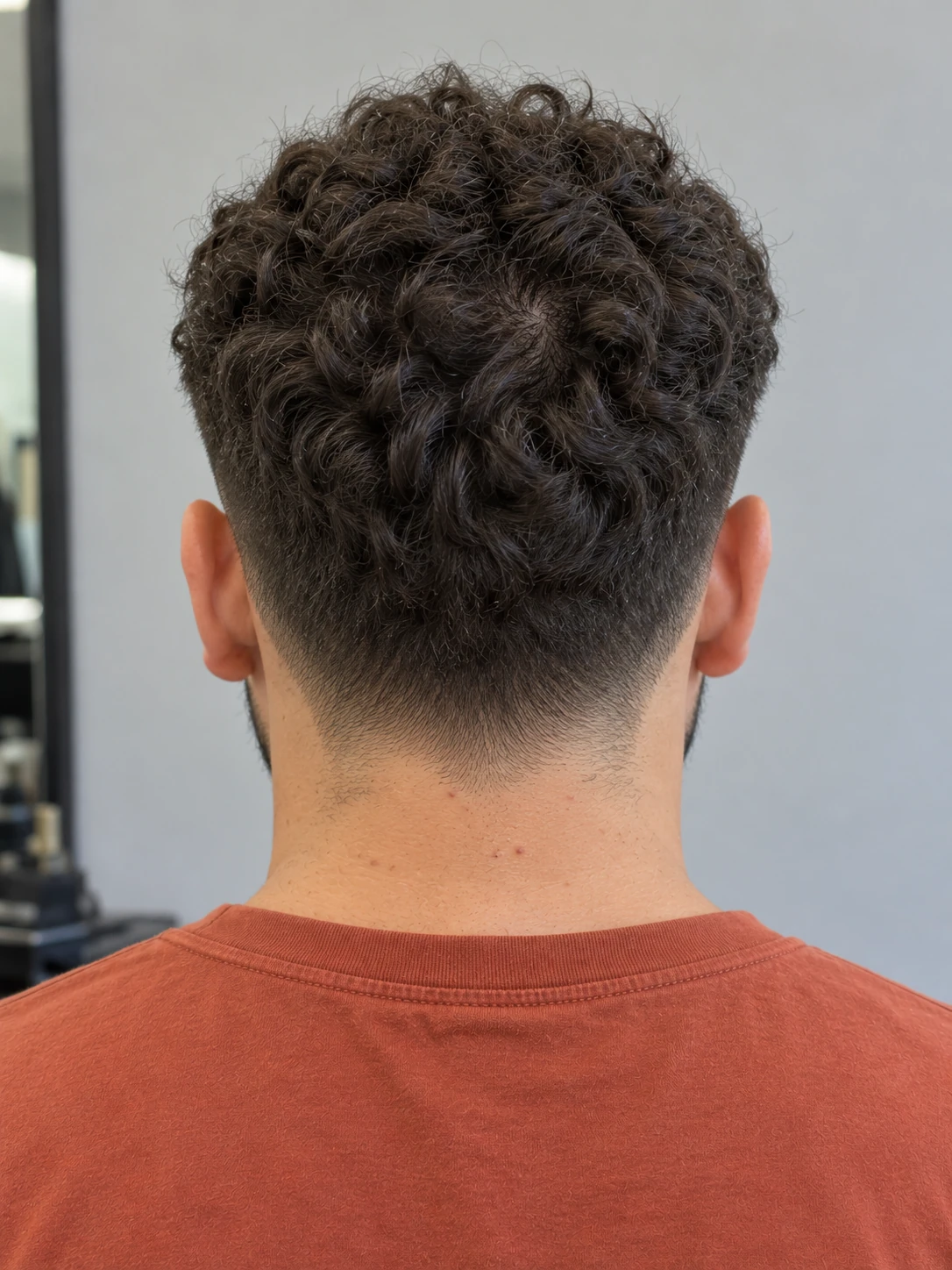AI concept: compact curly crop with a low taper, rear view.
